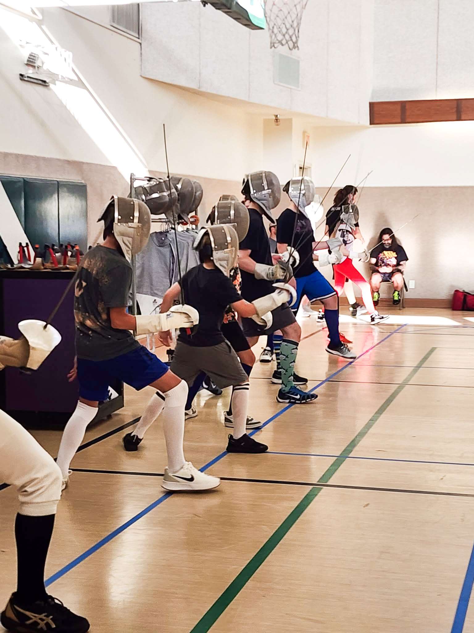 Fencers drilling footwork and blade work during a club class